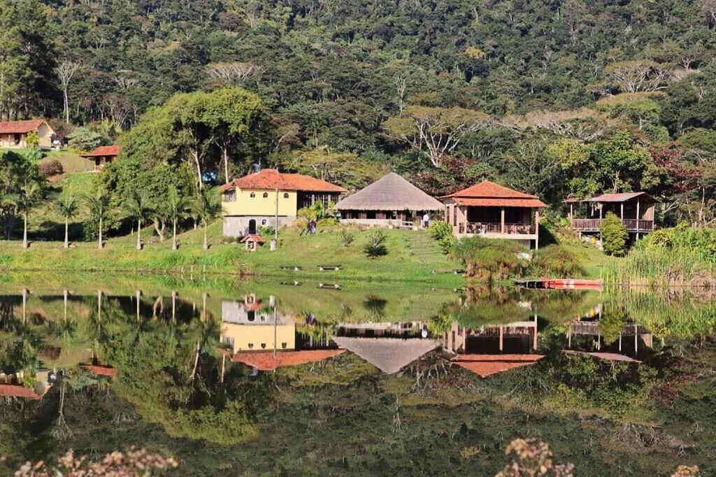 Casas do Hotel Fazenda Upã Moña refletidas no lago entre montanhas